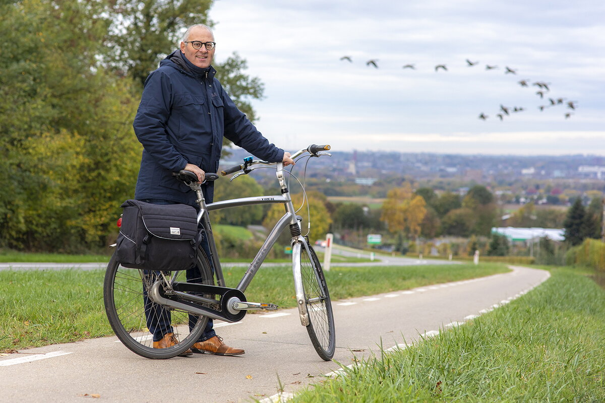 Rob Starren met de fiets aan zijn hand, kijkt lachend naar de camera