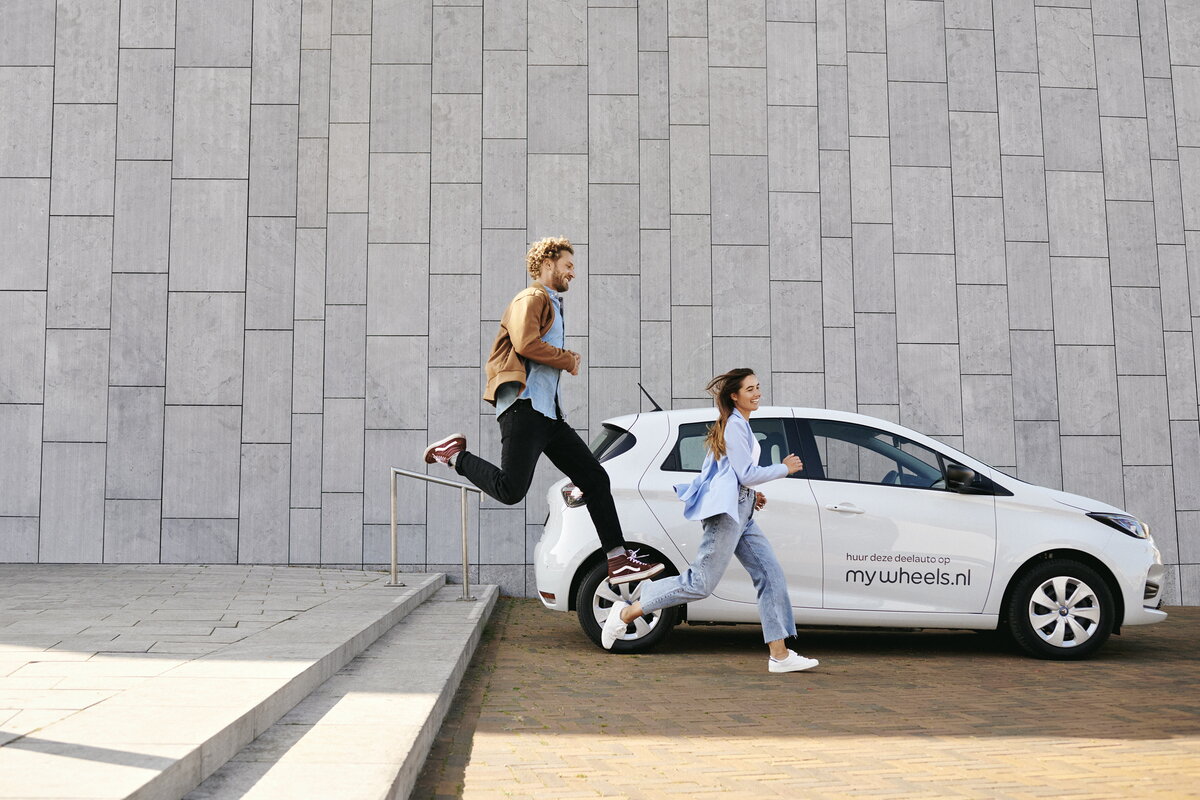 Mywheels deelauto met man en vrouw die lachend voorbij springen en rennen