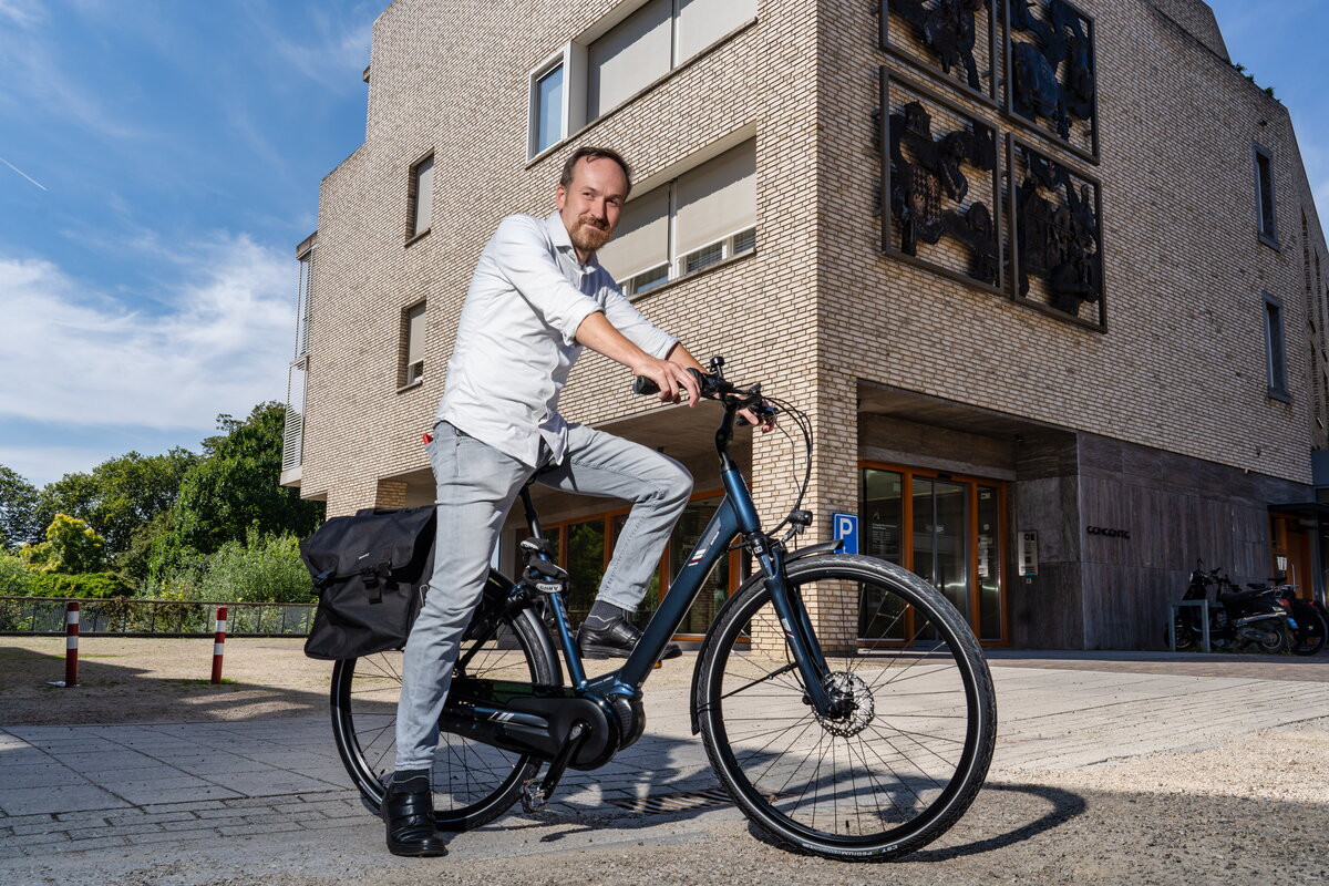 Jeroen Kuijpers op zijn fiets voor het gemeentehuis van Meerssen
