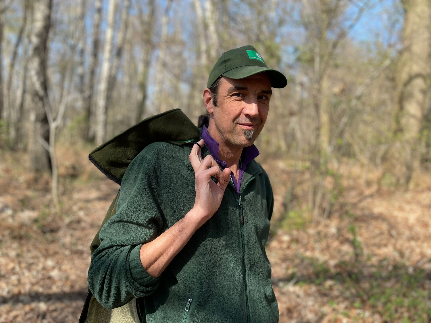 Stephan Huijgens in groen hemd en met groene pet, wandelend in de natuur