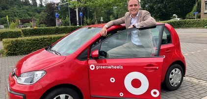 Wethouder Niels Dauven van gemeente Valkenburg bij een rode Greenwheels deelauto