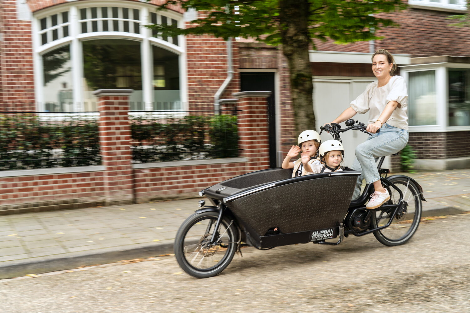 Sofie Leenders in actie, fietsend op bakfiets, met twee kindjes in de bak