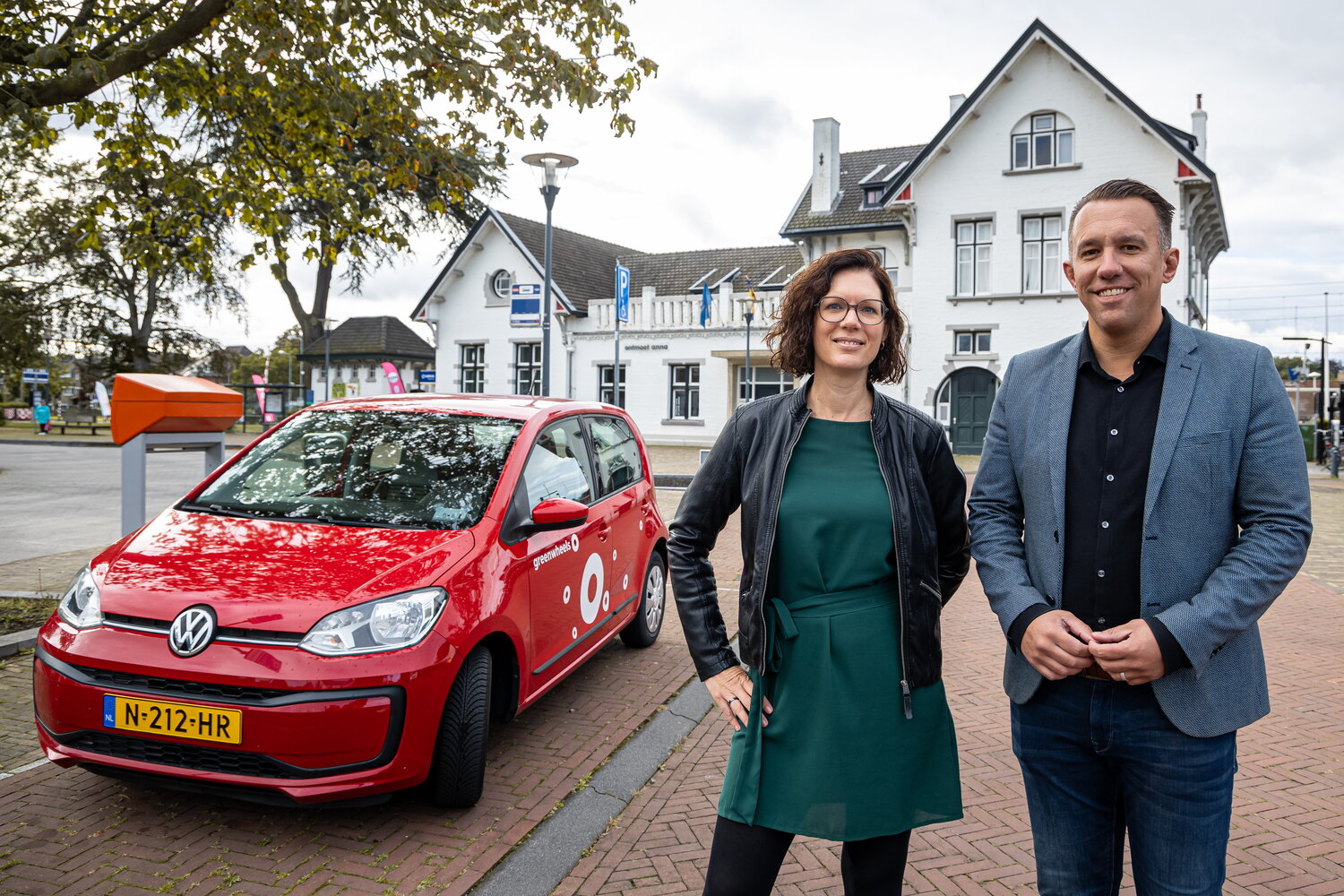 Rode Greenwheels deelauto en daarnaast de wethouders De Rond en Molling