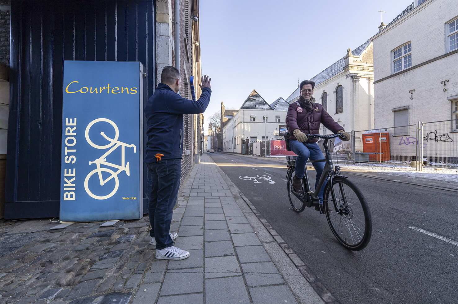 Jan Wouter Brunings vertrekt op de e-bike, bij fietshandelaar. Fietshandelaar zwaait hem uit